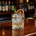 Craft gin cocktail with botanical garnish on a polished mahogany bar surface